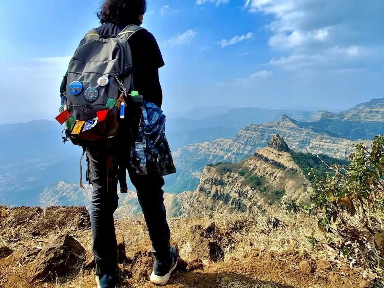 A trekker with a backpack looking out over the hills